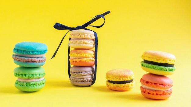 Pilas multicolores de macarons sobre fondo amarillo