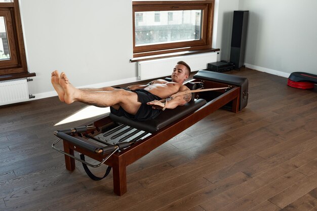 Pilates-Reformer-Trainingsübungen Mann im Fitnessstudio drinnen