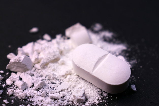 Píldora triturada sobre un fondo negro Primer plano Abuso de drogas