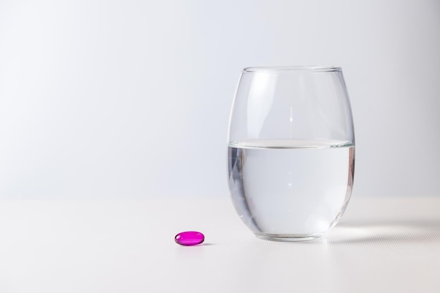 Una píldora con un vaso de agua concepto de salud y bienestar pandémico