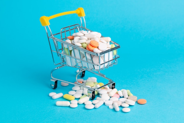 Píldoras antibióticas medicinales en carrito de compras en azul