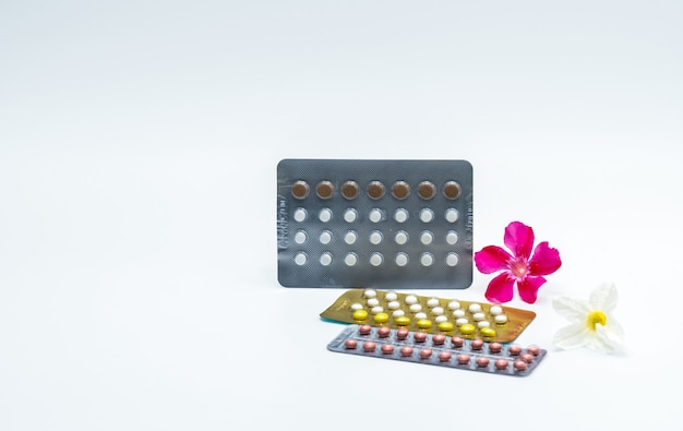 Foto píldoras anticonceptivas o píldoras anticonceptivas con flor rosa sobre fondo blanco con espacio de copia. hormona para la anticoncepción. concepto de planificación familiar. tabletas de hormonas redondas en blister.