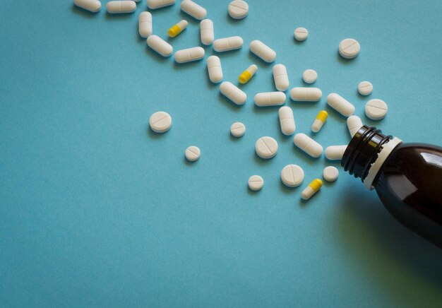 Píldoras blancas con botella oscura sobre fondo azul concepto médico concepto de enfermedad genética