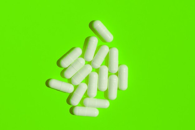 Píldoras blancas sobre un fondo verde brillante Vitaminas estilo de vida saludable Endecha plana