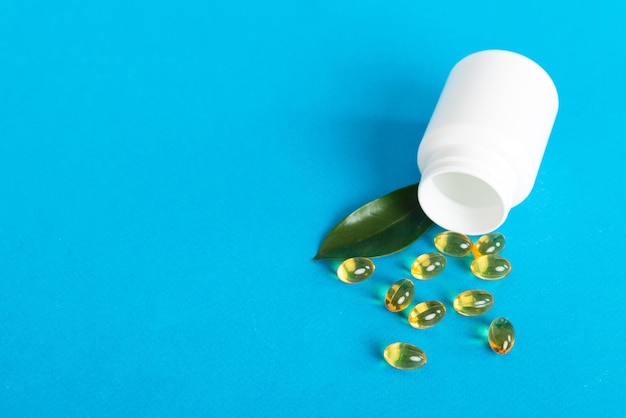 Píldoras blandas de gel con aceite Omega3 derramándose del frasco de pastillas closeup Cápsulas de gel botella superficie blanca Multivitaminas Omega 3 Antibióticos de calcio Salud Inmunidad