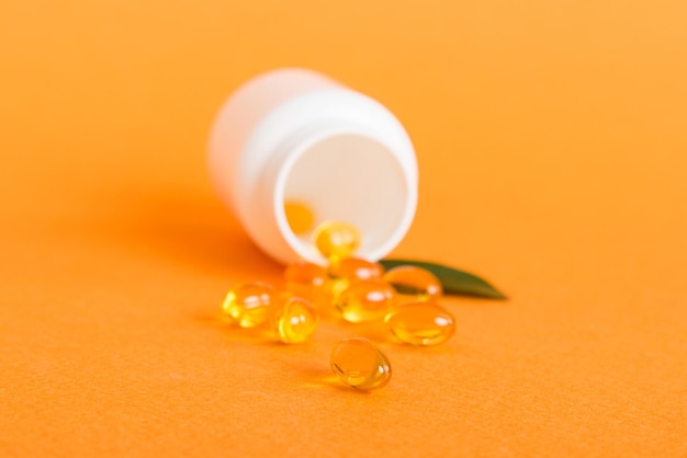 Píldoras blandas de gel con aceite Omega3 derramándose del frasco de pastillas closeup Cápsulas de gel botella superficie blanca Multivitaminas Omega 3 Antibióticos de calcio Salud Inmunidad