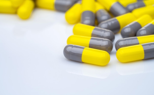 Píldoras de cápsula amarilla y gris de primer plano sobre fondo blanco Medicamentos recetados Industria farmacéutica