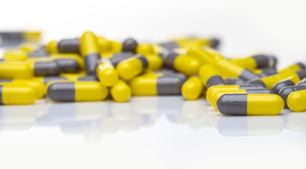 Píldoras de cápsulas amarillas y grises de primer plano sobre fondo blanco Medicamentos recetados Industria farmacéutica Concepto de atención médica y salud Productos de farmacia Fabricación de producción de píldoras de cápsulas