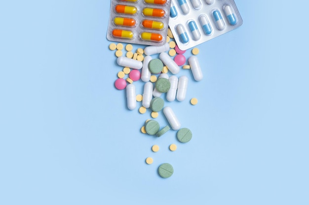 Píldoras de colores sobre fondo azul Concepto de salud y medicina plano laico