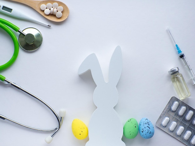 Píldoras en cuchara de madera conejo blanco y huevos de Pascua sobre fondo blanco