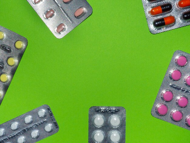 Píldoras de diferentes colores sobre un concepto de fondo verde de medicamentos Lugar para una inscripción Tratamiento médico Patrón de ampolla de píldora