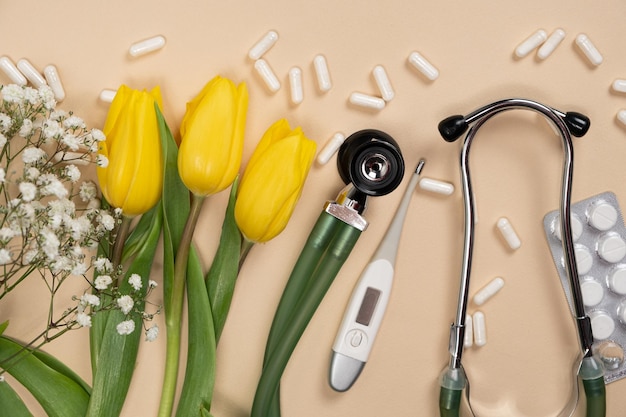 Foto píldoras y flores del estetoscopio de la medicina del día de fiesta en un fondo beige