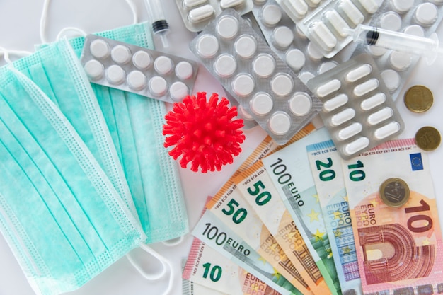 Píldoras médicas, billetes en euros, píldoras y modelo de coronavirus.