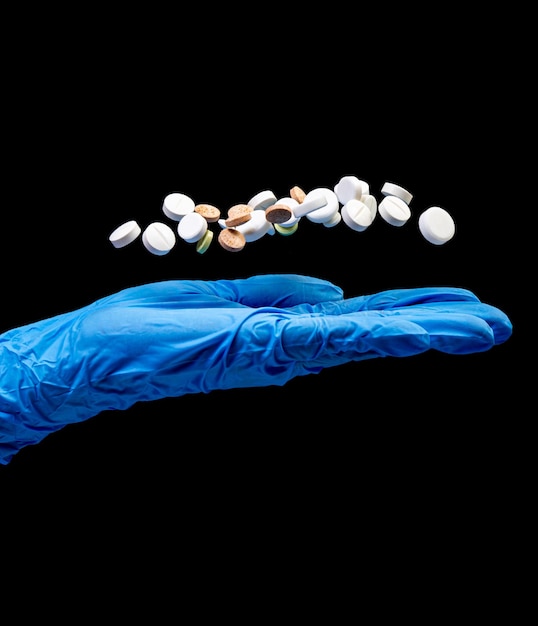 Foto píldoras médicas sobre un fondo negro aislado con reflejo caído de la mano
