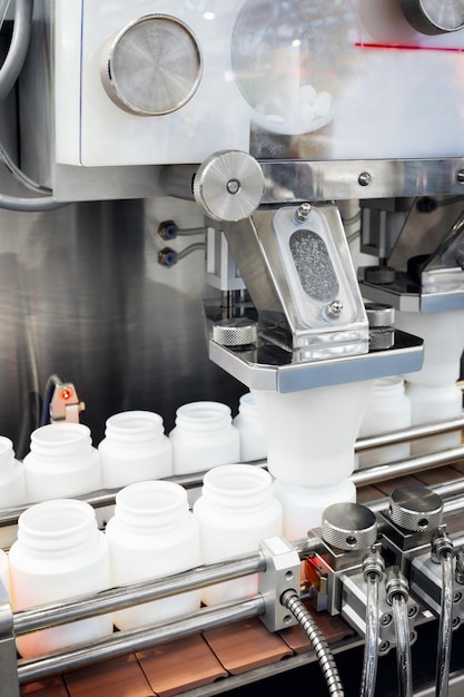 Las píldoras de medicina de la industria farmacéutica están llenando la botella de plástico en el transportador de la máquina de la línea de producción en el enfoque selectivo de la fábrica médica