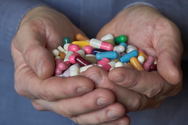 Foto píldoras multicolores en manos masculinas, concepto de protección farmacológica y salud.