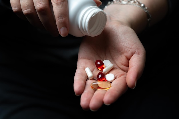 Foto píldoras multicolores o vitaminas se vierten en la mano desde una botella.