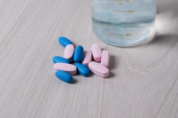 Píldoras o vitaminas probióticas azules y rosas sobre un tema de farmacología de fondo de madera