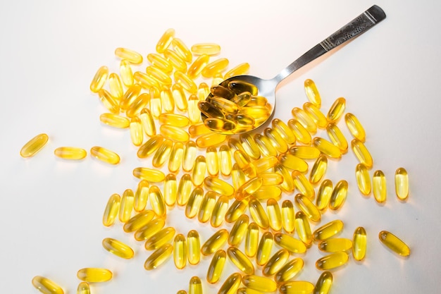 Píldoras de omega 3 en cuchara sobre fondo blanco de madera Suplementos dietéticos saludables Aceites de pescado para comida vegana