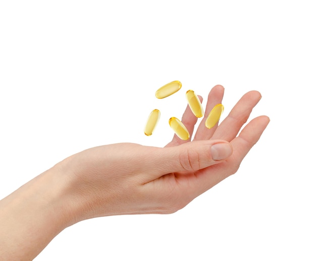 Píldoras de Omega 3 que flotan sobre la mano femenina aislada en el fondo blanco. Concepto de atención médica y tratamiento. foto de alta calidad