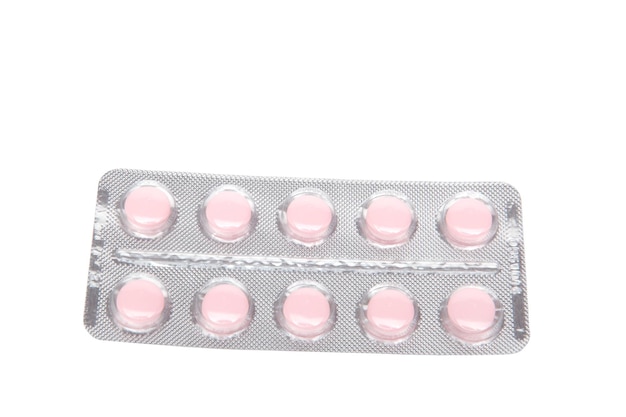 Píldoras de tableta rosa en blister aislado sobre fondo blanco.