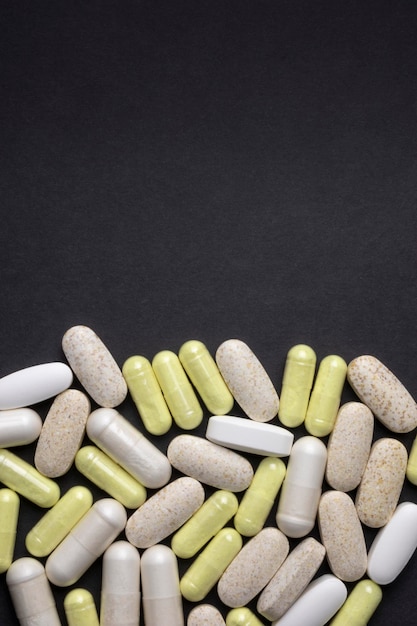 Píldoras, tabletas y cápsulas sobre fondo negro vertical plana Suplementos analgésicos