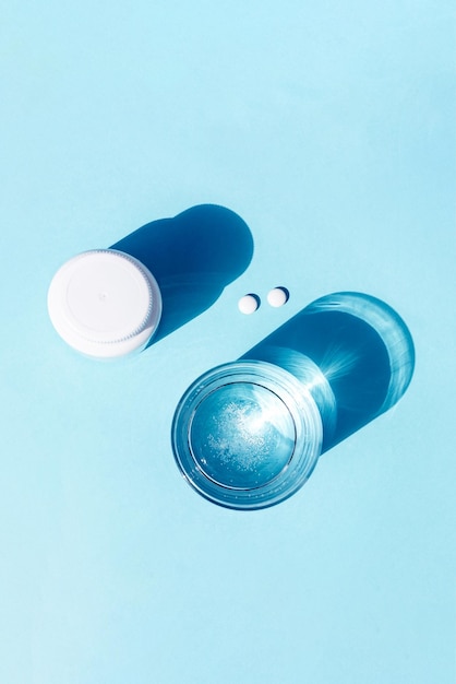 Píldoras y vaso de agua sobre fondo azul Medicina concepto de salud