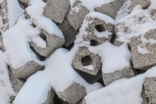 Pilha de blocos de concreto de tijolos de construção no canteiro de obras sob a neve