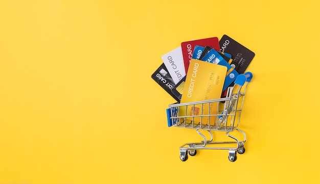 Pilha de cartões de crédito na cesta de compras em fundo amarelo Conceito de pagamento online