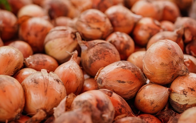 Pilha de cebolas laranja exibidas no mercado de comida de rua, detalhe aproximado