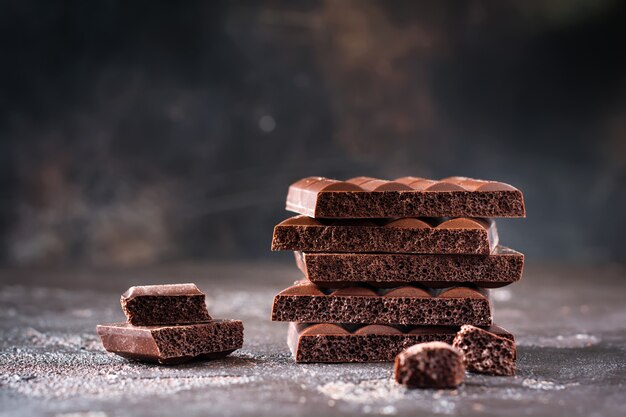 Pilha de chocolate amargo poroso e arejado na superfície escura e velha. foco seletivo.