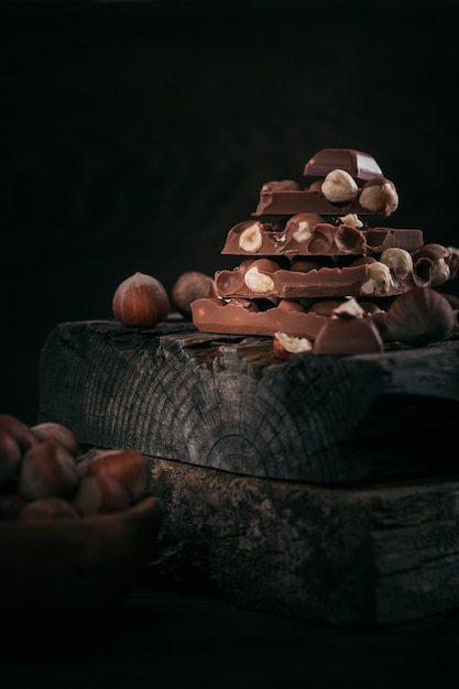 Pilha de chocolate com leite de avelã e nozes em fundo escuro