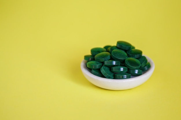 Foto pilha de close-up de pílulas de spirulina verde