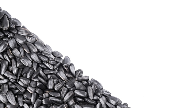 Pilha de close-up de sementes de girassol pretas em um fundo branco com espaço de cópia