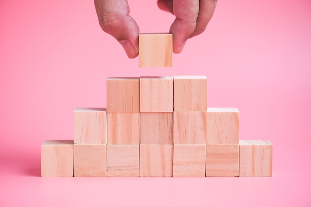 Foto pilha de construção de mão de homem de blocos de construção de madeira cubo