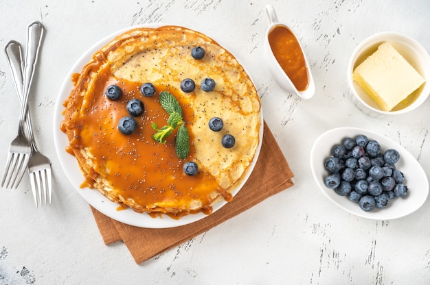 Pilha de crepes caseiros cobertos com caramelo e mirtilos frescos