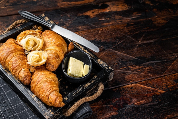 Pilha de croissants amanteigados franceses com manteiga na bandeja de madeira Fundo de madeira Vista de cima Copie o espaço