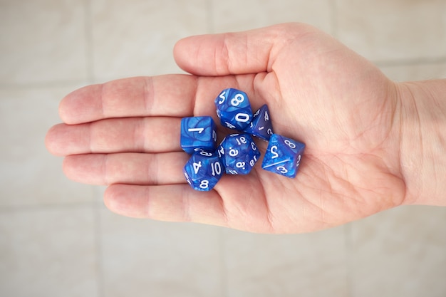Pilha de dadinhos de cor azul para role playing game na palma da mão, vista de cima