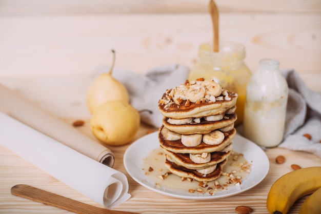 Pilha de deliciosas panquecas com mel, nozes e fatias de banana.