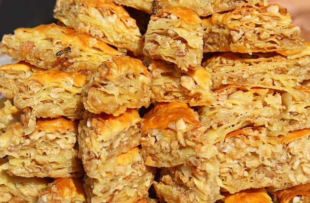 Pilha de deliciosos bolos Baklava atraindo pequenas abelhas no mercado local da Armênia