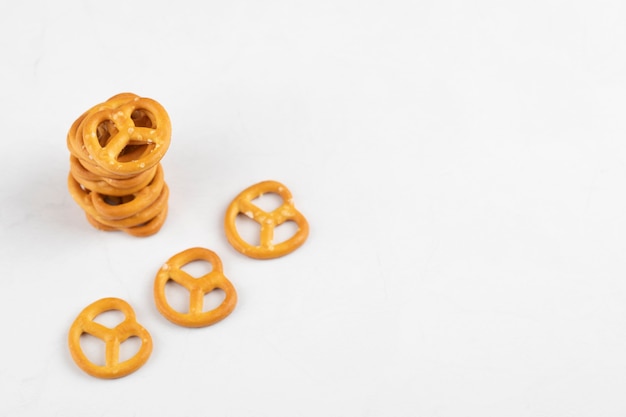 Pilha de deliciosos pretzels secos com sal na superfície branca