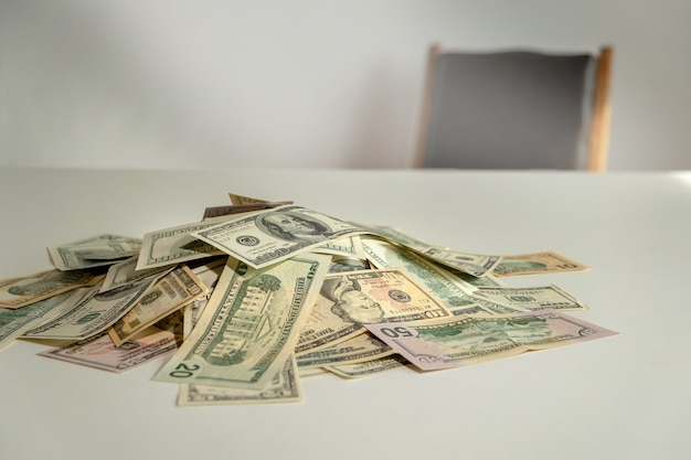 Foto pilha de dólares com cadeira no fundo. dinheiro na mesa. conceitos de suborno, propina, corrupção e venalidade empresarial.