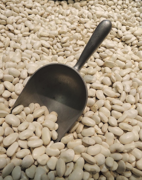 Pilha De Feijão Cannellini Com Colher De Medição De Metal Para Mercadorias A Granel Foto De Stock