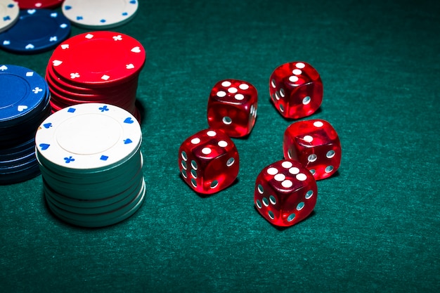 Foto pilha de fichas de casino e dadinhos vermelhos na mesa de poker