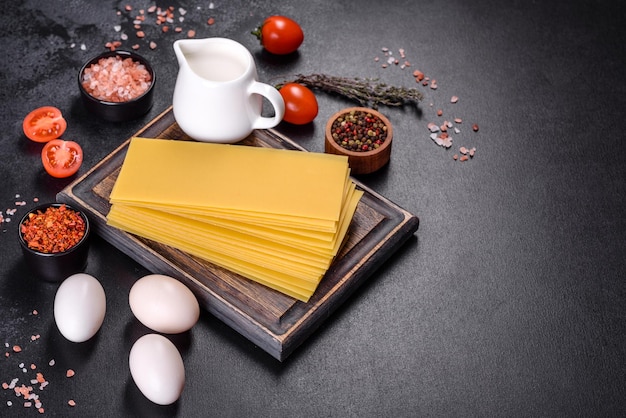 Pilha de folhas de lasanha em um fundo escuro de concreto Ingredientes para lasanha