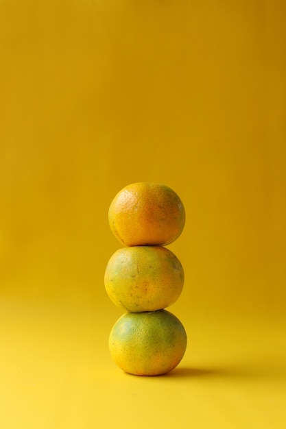 Pilha de frutas laranja dispostas em fundo amarelo Copie o espaço para produção agrícola e alimentos saudáveis