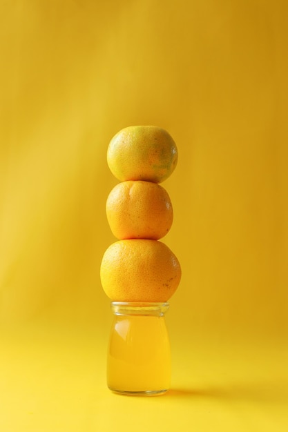 Pilha de frutas laranja no fundo amarelo do frasco Conceito de bebida fresca e saudável no verão