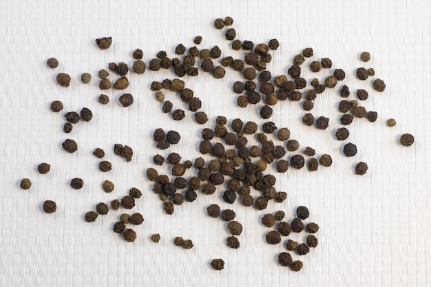 Foto pilha de grãos de pimenta preta sementes secas de pimenta preta em fundo texturizado branco