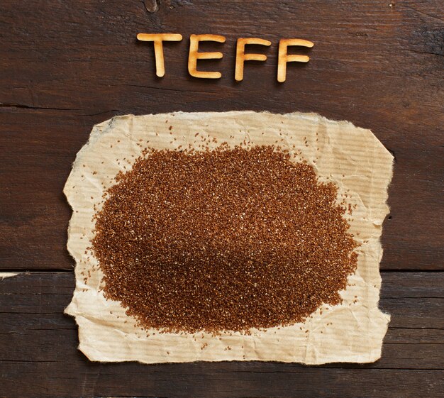 Pilha de grãos teff crus com uma colher de perto