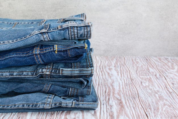 Pilha de jeans elegantes em uma mesa de madeira com espaço de cópia